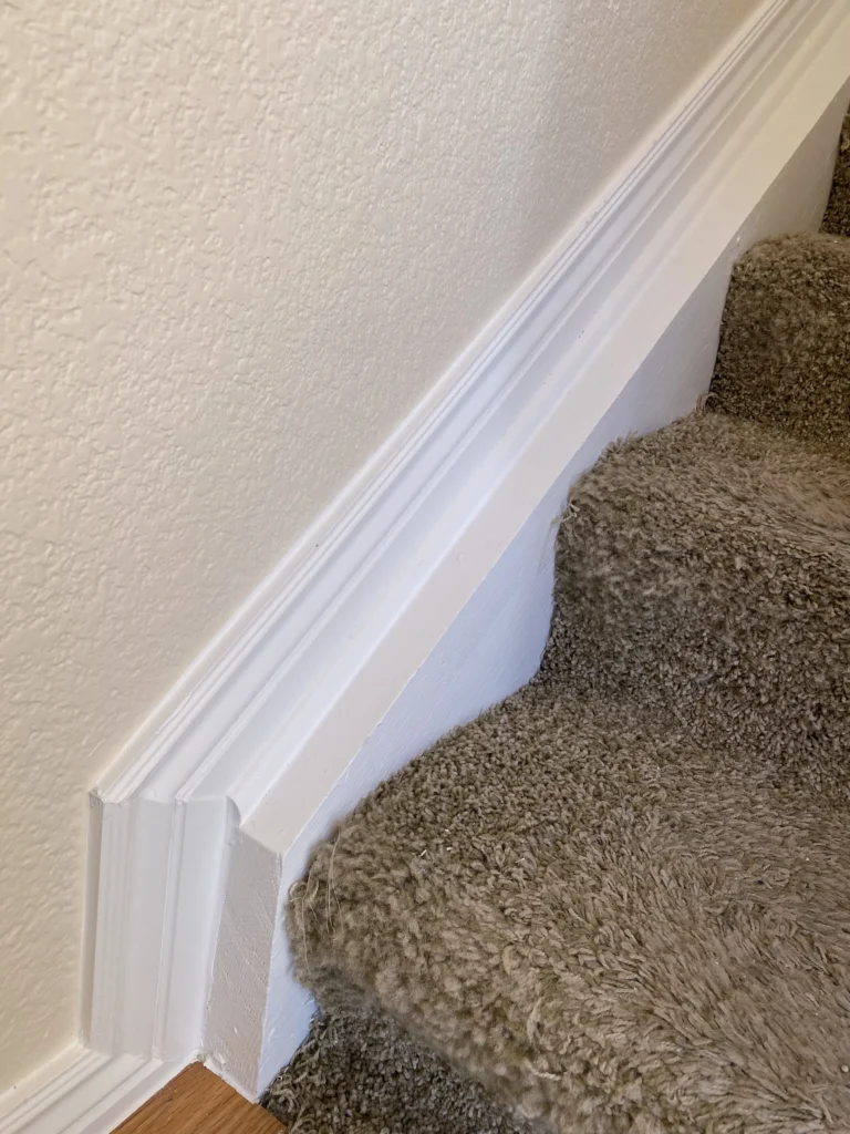 Carpeted stairway with freshly painted white baseboards