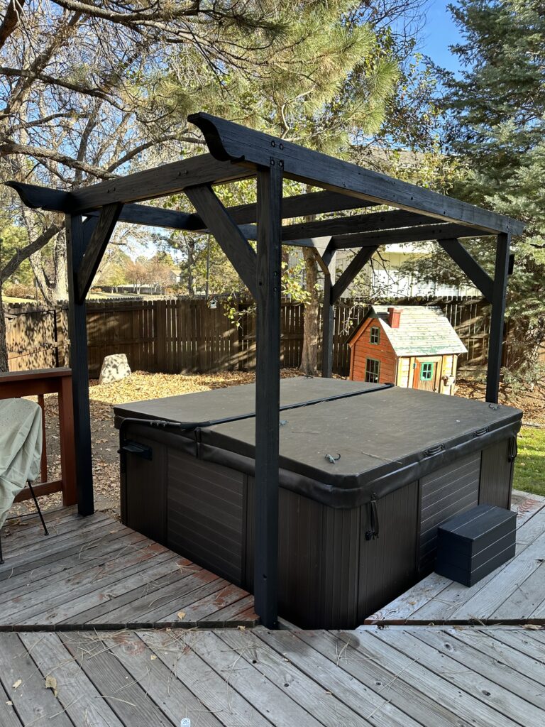 A dark stained wooden pergola over a hot tub